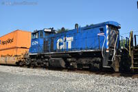 An end cab switcher, presumably on a relocation move, rides behind the mainline power of the stack train